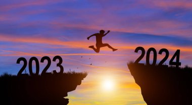 Mutlu Noeller ve 2024 yılına hoş geldiniz. 2023 'ten 2024' e kadar Sunset ve Twilight Sky arka planına sahip uçurumdan atlayan adam..