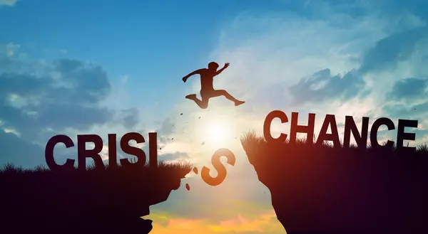 Silhouette man jumping form cliff with Crisis word to another cliff with Chance word. Successful and Achievement Concept. Copy space.