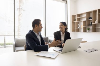 Birkaç Hintli profesyonel iş arkadaşı laptopta konuşuyor, Jo 'nun başarısını tartışıyorlar, başarılı takım çalışması, proje üzerinde beyin fırtınası yapıyorlar, online teknolojiyi işbirliği için kullanıyorlar.