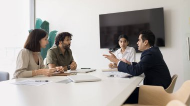Çeşitli iş arkadaşları proje, yönetim stratejisi, toplantı salonundaki masada çalışma konusunu tartışıyor. Genç Hintli lider kadın ortaklarla pazarlık yapıyor.