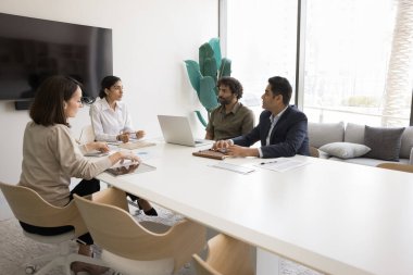 Hintli genç işletme koçu kadın çeşitli çalışanlarla beyin fırtınası toplantısı yapıyor, toplantı odasında seminer veriyor. Çok ırklı proje ortakları anlaşma ve ortaklığı tartışıyor