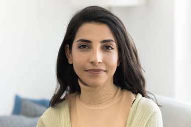 Mutlu 30 'lu yılların güzel Latin kadını dostça gülümseyerek kameraya bakıyor. Evde poz veren güzel siyah saçlı İspanyol kadın model vesikalık fotoğraf portresi.
