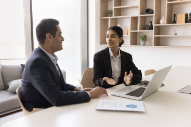 İki Hintli iş arkadaşı işbirliği, proje stratejisini tartışıyor, başlangıç fikirleri üzerinde beyin fırtınası yapıyor, dizüstü bilgisayarla konuşuyor, iş yerinde oturuyor, takım çalışması için buluşuyor, işbirliği yapıyor.