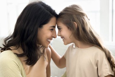 Sevgi dolu bir anne ve mutlu bir kızın kafa teması, gülümseme, gülme, yakınlık, güven, sıcak bir ilişki, aile sevgisi ile kucaklaşması. Yan görünüm gizli çekim