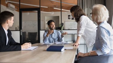 Mutlu genç Hintli takım lideri toplantı masasında çalışanlarla konuşuyor, proje fikirleri üzerine beyin fırtınası yapıyor, işbirliği, pazarlama planı, strateji tartışıyor, patronların yerinde oturuyor, gülümsüyor. Sancak vuruşu