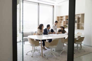 Genç bayan liderli çok ırklı iş adamları takım çalışması için yaratıcı fikirler üzerinde kafa patlatıyorlar, proje üzerinde işbirliği yapıyorlar, büyük ofis masasında buluşuyorlar, konuşuyorlar.