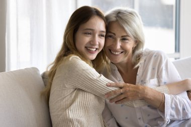 Sevgi dolu genç kız orta yaşlı anneye sarılıyor, sevinç anlarını paylaşıyor, birbirine eşlik ediyor, anne ve çocuk aile bağıyla birleşiyor, koşulsuz sevgi hissediyor, yakın portre