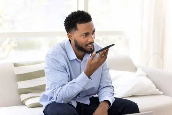 Joven Hombre Negocios Negro Serio Sosteniendo Teléfono Inteligente Boca Dictando —  Fotos de Stock