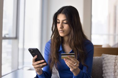 Genç Hintli banka müşterisi kadın kredi kartı bilgilerini akıllı telefondan bankaya yerleştiriyor, internet üzerinden online alışveriş yapıyor, internetten alışveriş yapıyor, para transferi yapıyor.