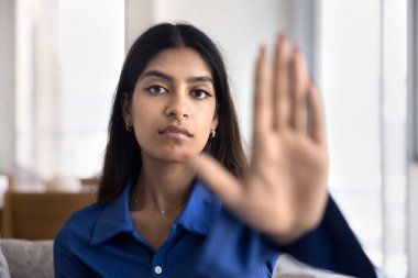 Ciddi kararlı genç Hintli kadın dur işareti gösteriyor, kameraya avucunu aç, dur, reddet, tehlike, reddedilme, kısıtlama el hareketi. Bulanık kolu kadın modeliyle kapat.