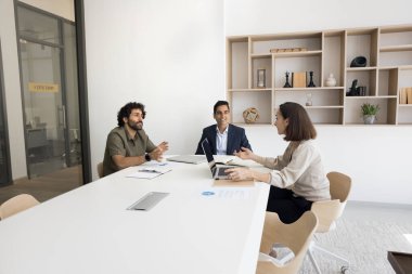 Çeşitli meşgul iş arkadaşları toplantı odasında büyük masada konuşuyorlar, dizüstü bilgisayar kullanıyorlar, iş stratejisi, ortaklık, anlaşma, işbirliği tartışıyorlar.