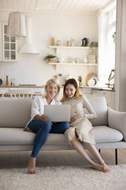 Mutlu genç kız, orta yaşlı annesiyle birlikte oturma odasında oturuyor sosyal medyada komik videolar izliyor, internette geziniyor, aile hafta sonunun tadını çıkarıyor. İki farklı nesil modern teknoloji kullanıyor.