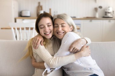 Sevgi dolu orta yaşlı bir anne, genç kızına sarılıyor kanepeye oturuyor, mutlu hissediyor, ilgi gösteriyor ve destek oluyor, evde birlikte dinleniyorlar. Pozitif kız, annesiyle geçirdiği hassas anlardan zevk alır. Annelik, ilişki, bağlar.