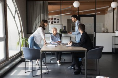 Happy toplantıda konuşan, ayakta ve masada oturan, konuşan, gülümseyen, gülen, beyin fırtınası için motive edici fikirleri tartışan çok ırklı genç ve yaşlı meslektaşlarına ilham verdi. Tam boy çekim