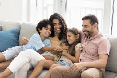 Neşeli ebeveynler evde küçük çocukları kucaklıyor, aktif oyunlardan, boş zamanlardan, çocuklarla aile aktivitelerinden keyif alıyor, gülüyor, kıkırdayan oğluyla ve kızıyla eğleniyor.