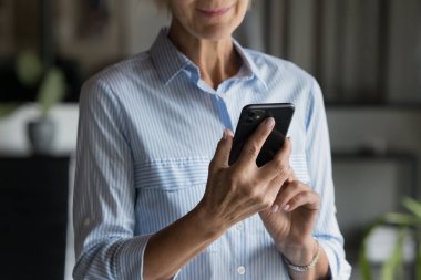 Olumlu yaşlı iş kadınlarının cep telefonuyla yazması, internet uygulaması, online banka servisi, mesaj atması, sohbet etmesi, arama yapması, video izlemesi, sosyal medyayı karıştırması. Kırpılmış atış