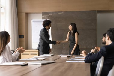 Mutlu iş ortakları şirket toplantısında el sıkışıyor, meslektaşlarından alkış alıyor, başarılı bir iş birliğinin keyfini çıkarıyor, takım çalışması yapıyor, başarıyı kutluyor.