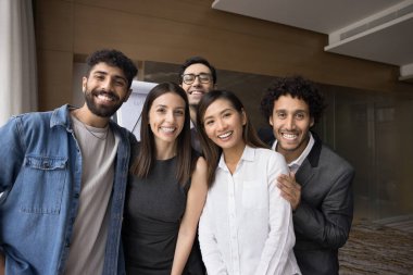 Ofis arkadaşlarının neşeli çoklu etnik grupları birbirlerine yakın durup kameraya bakıp gülümsüyor ve gülüyorlar. Başarılı iş arkadaşları portre için poz veriyor, kurumsal arkadaşlığın tadını çıkarıyor.