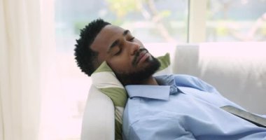Kapalı yerde uzanan Afrikalı bir adam, evdeki kanepede uyur, sağlıklı bir uyku çeker kaygısız görünür, derin rüyalar görür, dinlenir, dinlenir, yorgunluğu hafifletir izin günlerinde ya da iş gününden sonra oturma odasında. Rahatlama