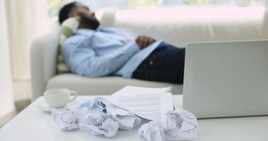 Dağınık kağıtları laptopla birlikte dağınık masanın üzerine koy, yorgun Afrikalı iş adamı kanepede uyuyor bitkin düşmüş ve tamamlanmamış projeyle uykuya dalmış görünüyor. Son teslim tarihi, stresli iş