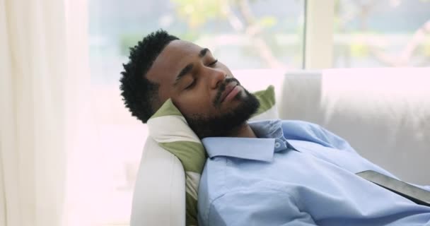 把非洲男人关在室内 睡在家里的沙发上 白天睡得很健康 看起来很无忧无虑 做了很久的梦 下班或下班后在客厅里减轻疲劳 放宽管制 — 图库视频影像