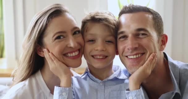 可爱小男孩的近脸触摸着慈爱的父母的双颊 微笑着 看着相机 拥有完美的牙齿和迷人的外表 为牙科服务做广告 展示家庭关系 — 图库视频影像
