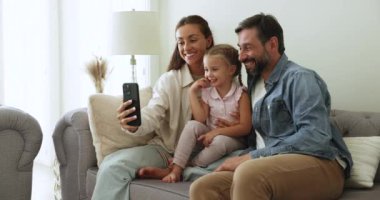 Hafta sonları evde akıllı telefon kullanan, kanepeye oturup cihaz ekranına bakan, uzaktan konuşmanın keyfini çıkaran, yeni mobil uygulamanın keyfini çıkaran, küçük 4 'lü kızlı ebeveynler.