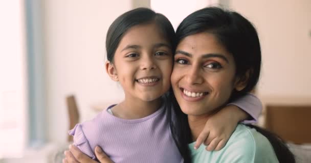 インドの若い母親の美しい顔が彼女の愛らしい小さな5Sの娘を抱きしめました 子供の肖像画はカメラを見てかわいいお母さんの笑顔を抱きしめ ハーモニックで愛情深い関係を楽しんでいます — ストック動画