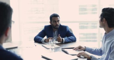 Takım elbiseli Hintli işadamı, takım lideri, patron, ofis ortaklarıyla resmi toplantı, konuşma, fikir ve çözüm paylaşımı, bilgi sağlama, şirket müşterilerini hizmet satın almaya ikna etme