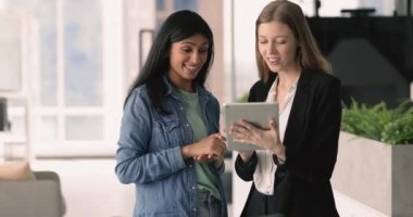 İş akışlarında yapay zeka uygulamasını kullanan genç kadınlar fikir ve çözümler üretiyor, ortak görev üzerinde çalışıyor, modern tablet ekranına bakarak pazarlama stratejisini tartışıyorlar.