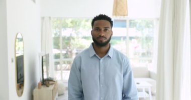 Kendine güvenen yakışıklı Afrika milenyumu erkeğinin resmi evde duruyor, oturma odasında tek başına duruyor kameraya bak, memnun müşteri hizmetleri, erkek blogcu ve serbest çalışan, ev sahibi portresi