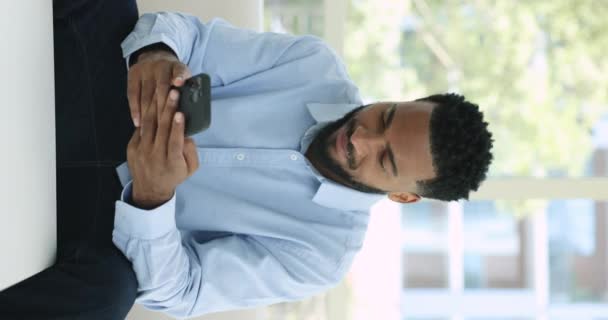 Szczęśliwy Afrykanin Siedzieć Kanapie Posiada Telefon Komórkowy Odbierać Wiadomość Czytać — Wideo stockowe