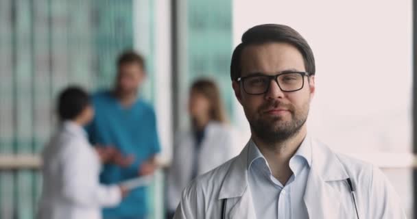 Mužský Praktický Lékař Bílém Lékařském Kabátě Usmívá Kameru Pózuje Klinice — Stock video