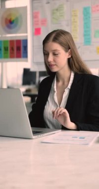 Kadın laptopta çalışıyor, iş akışına dalmış, müşteriye ya da meslektaşına e-posta yazıyor, yaklaşan toplantı için rapor ya da sunum yaratıyor, verileri güncelliyor, belgeleri gözden geçiriyor ve düzenliyor