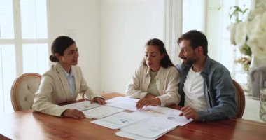 Mali konularla ilgili resmi toplantı. Gayrimenkule yatırım yapmayı düşünen eşler, onlara pazar verileri, emlak listeleri ve yatırım analizleri sunan temsilciler, çizelge ve istatistiklerle dolu kağıtları tartışırlar.