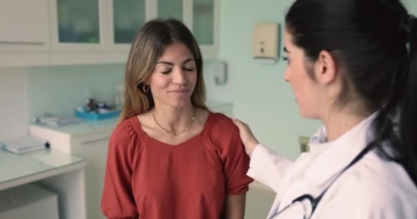 在私人诊所看病期间 支持女病人的年轻治疗师摸她的肩膀 提供心理支持 解释疾病诊断 图库视频片段