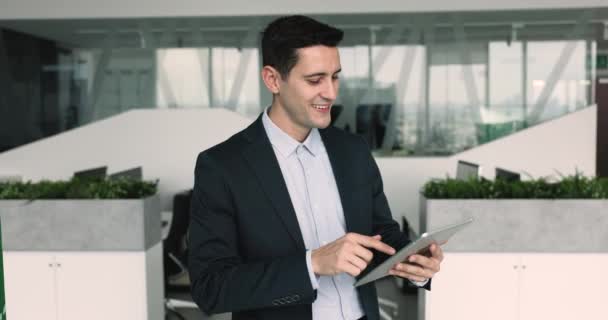 コワーキングオフィスのデジタルタブレットを使用して正式なスーツのハンサムスペイン人ビジネスマン 最新の無線技術を使用したワークフロー オンラインプロジェクトの準備 オンラインで働くマーケティング部門の従業員 — ストック動画