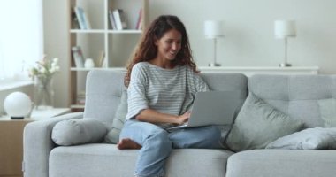 Latin kökenli genç bir kadın oturma odasında dizüstü bilgisayarla dinleniyor, hafta sonu evde boş vakit geçiriyor çevrimiçi iletişimin tadını çıkarıyor, sosyal medyada sohbet ediyor, mesajlarımı arkadaşlarıyla paylaşıyor, sipariş veriyor.