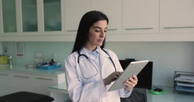 Tıbbi ofiste dijital tablet kullanan kadın terapist, önemli bilgileri kaydedin, hastalara teletıp danışmanlığı sağlayın, uygulamaları kullanın, randevu ayarlayın, hatırlatıcı ayarlayın, iş akışını organize edin