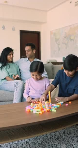 印度家庭在客厅里休息 小兄弟姐妹们用塑料砌成 父母坐在沙发上聊天 可爱孩子的业余时间和爱好 父母的交流 — 图库视频影像