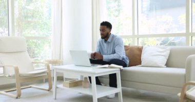 Milenyum Afrikalı iş adamı, evdeki koltukta oturup video görüşmesiyle resmi konuşmaları yönetiyor. Çevrimiçi danışmanlık etkinliği, istemciye danışma video konferans uygulaması ve bilgisayar