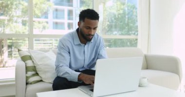 Afrikalı adam dizüstü bilgisayarla kanepede oturur, e-posta okur iş başarısını kutlar, inanılmaz mutlu olur, kariyer terfisi alır, güzel bir reklam teklifi alır, internet piyangosunun tadını çıkarır, kazanır, zafer kazanır.