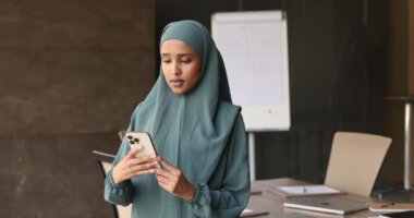 Geleneksel tesettürdeki Somalili Müslüman iş kadını akıllı telefonu iş yerinde tut, müşteriye mesajla cevap ver, ajandanı kontrol et, takvime not al, iş için yeni cep telefonu uygulaması kullan