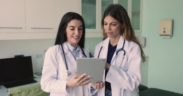 デジタルタブレットを使用する2人の女性Gpの同僚は 患者の症例を議論し アプリケーションを使用して最適な治療計画を策定します ワークフローとチームワークは 現代の技術 スキル 知識交換を使用しています — ストック動画