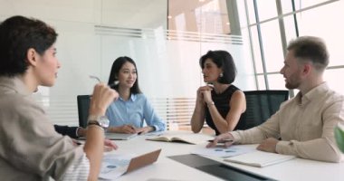 Çeşitli takımlar ve genç Asyalı bayan patronlar proje üzerinde birlikte beyin fırtınası yapıyorlar, yaratıcı fikirleri, takım çalışmasını, iş görevlerini, gülmeyi, eğlenmeyi, toplantı masasında konuşmayı tartışıyorlar.