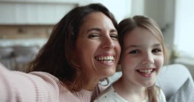 Sevgi dolu genç bir anne evde tatlı kızıyla rahatlar, kameraya bakıp video kaydeder, poz verir, sıcak aile ilişkisinin tadını çıkarır, birlikte mutlu bir şekilde dinlenir. Aile portresi, annelik, blog yazma