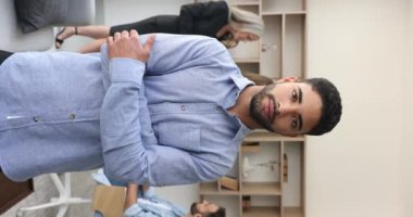 İş perspektifleri, şirkette kariyer gelişimi. Dikey görünüm gülümseyen Faslı adam, çalışanlar, yeni çalışan ofiste kamera görüntüsü, arka planda çalışma arkadaşları, tatmin olmuş hissediyor.