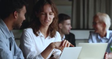 Dizüstü bilgisayarla konuşan, toplantı masasında oturan ve ekranı işaret eden çok ırklı genç iş arkadaşları. Pozitif Hintli akıl hocası eğitimi dinliyor, bilgisayardaki stajyer kadını selamlıyor.