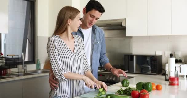 美しいラテンカップルが話す 現代のキッチンで一緒に料理 自然の野菜から健康的なベジタリアンサラダを準備 カドリング 彼らの愛を楽しむ ロマンチックなデートと良い調和の関係 動画クリップ