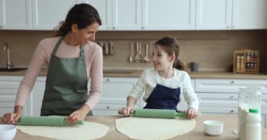 Güzel bir anne ve küçük kızı ev yapımı tatlı için hamur düzleştiriyor. Mutfakta birlikte yemek pişirmekten mutluluk duyarken, yemek pişiriyor, eğleniyor, gülüyor ve eğleniyorlar. Aile tarifi